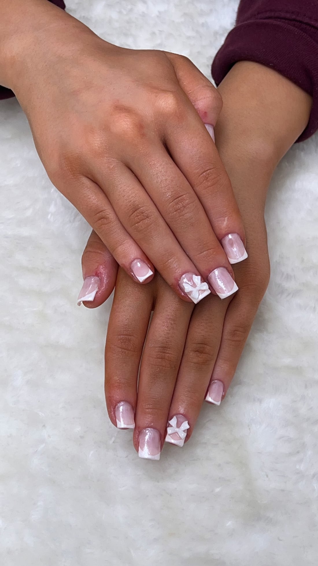 Pink French tip nail art with delicate bow details, photographed at the salon